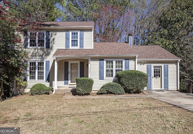 view of front of home featuring a chimney, a shingled roof, and a front yard