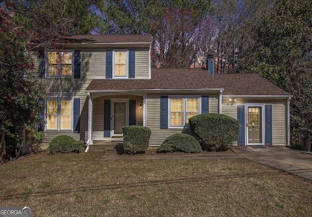 traditional-style house featuring a shingled roof and a front lawn