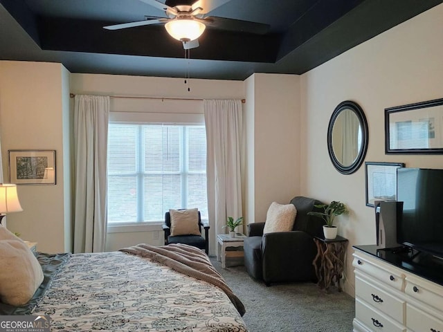 carpeted bedroom with a tray ceiling and ceiling fan