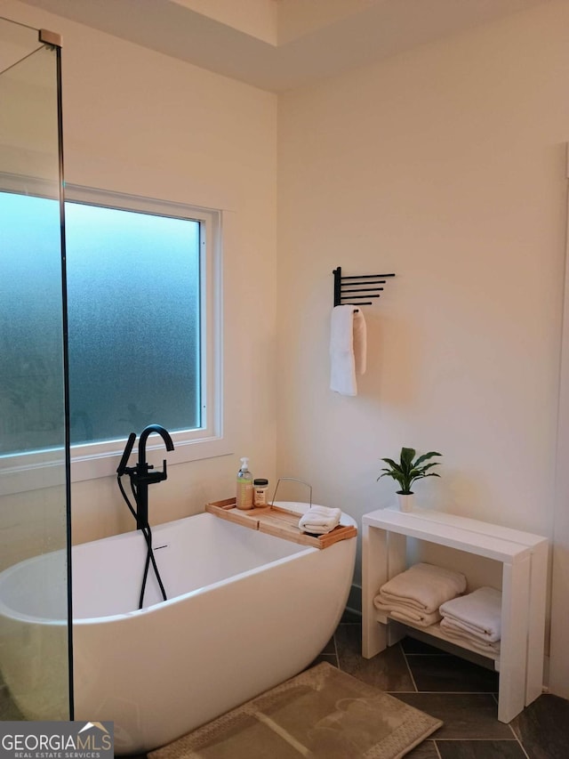 full bath featuring tile patterned floors and a soaking tub