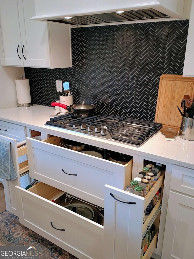 kitchen with white cabinetry, backsplash, and stainless steel gas cooktop