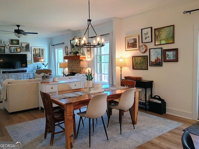 dining space featuring light wood-style flooring, a fireplace, baseboards, and ornamental molding