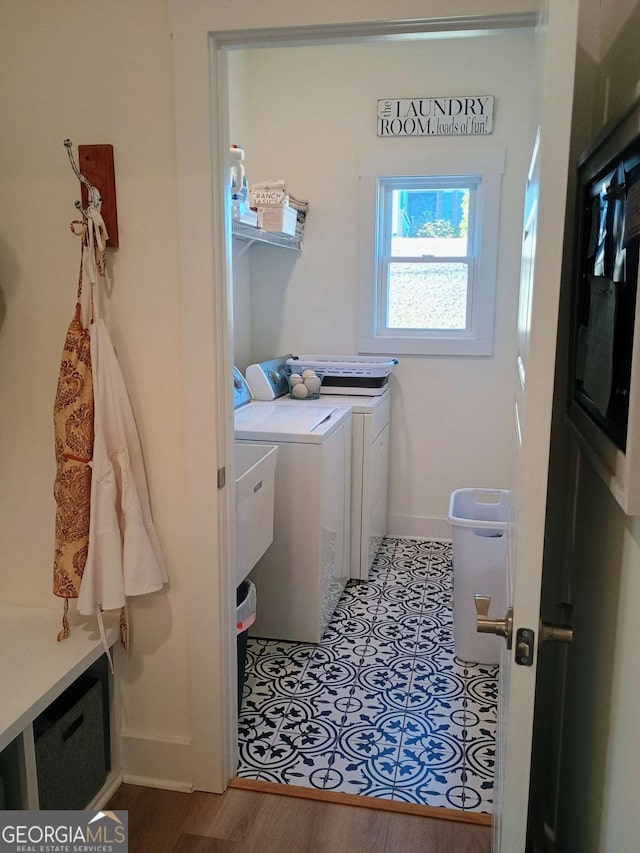 washroom featuring baseboards, wood finished floors, laundry area, and washing machine and clothes dryer