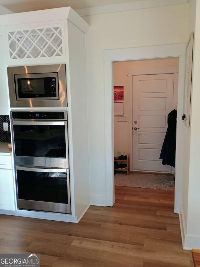 kitchen featuring baseboards, appliances with stainless steel finishes, and wood finished floors