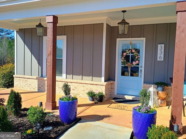 entrance to property with a porch, board and batten siding, and brick siding