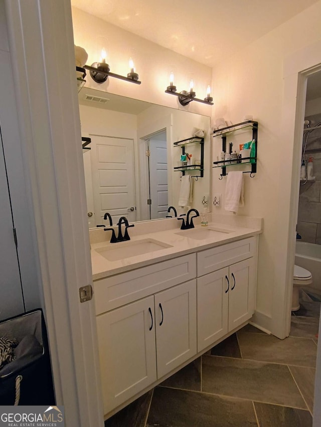 full bath with double vanity, visible vents, toilet, and a sink