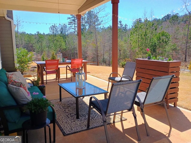 view of patio featuring outdoor dining space, a forest view, and outdoor lounge area