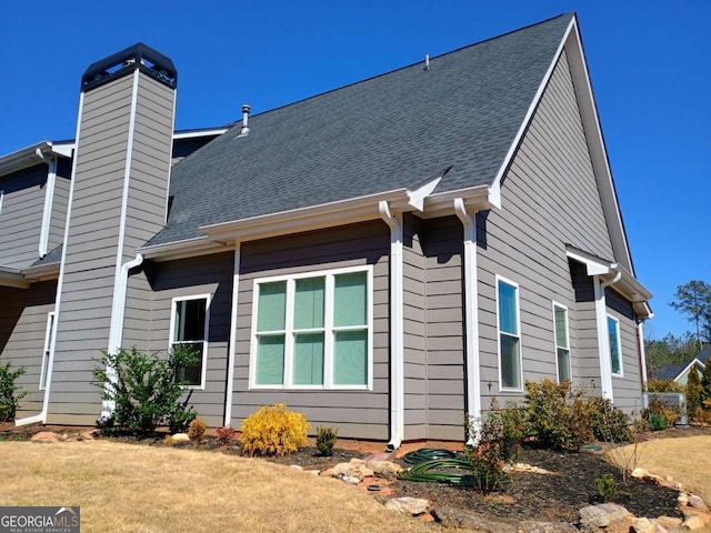 back of property with a chimney and a shingled roof