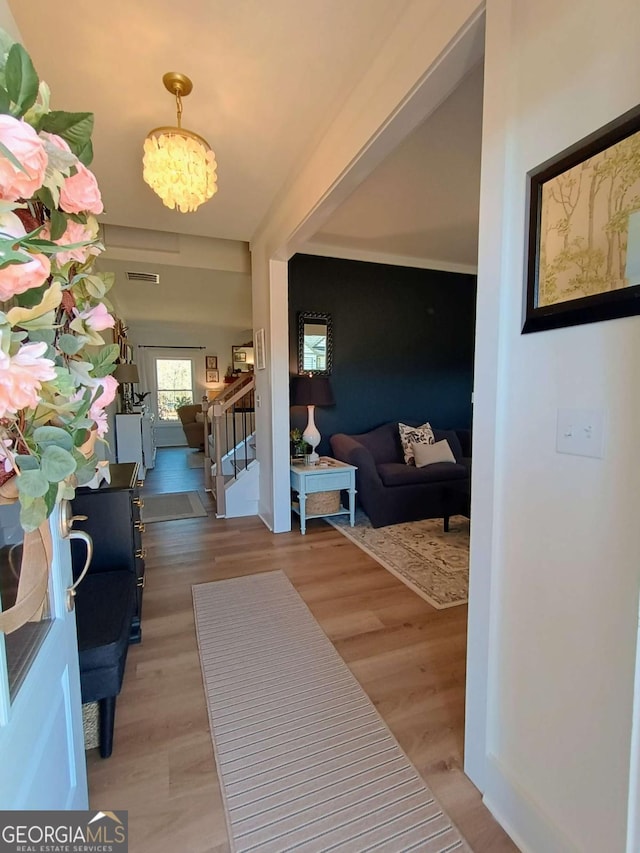 foyer entrance with a chandelier, stairway, light wood-style flooring, and visible vents