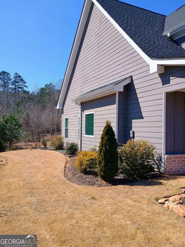 view of home's exterior featuring a yard and roof with shingles