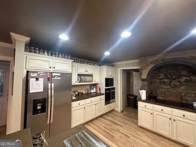 kitchen featuring dark countertops, appliances with stainless steel finishes, light wood-style floors, and ornamental molding