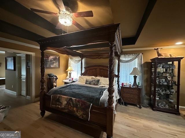 bedroom with wood finished floors, a ceiling fan, and crown molding