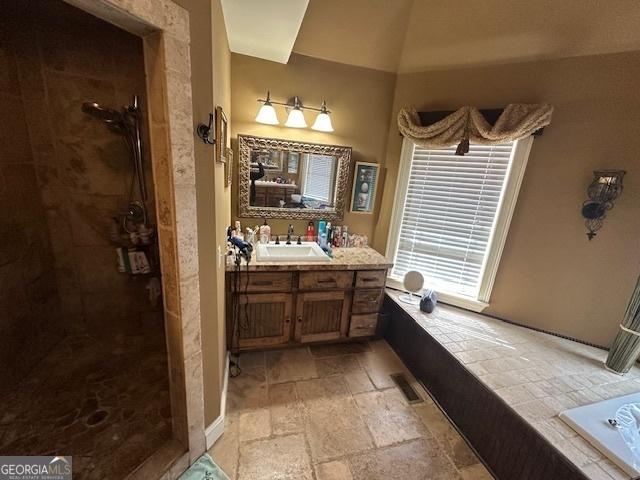 full bath featuring vanity, tiled shower, visible vents, and stone tile flooring