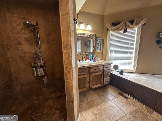 full bathroom featuring vanity, visible vents, a tile shower, and stone tile flooring