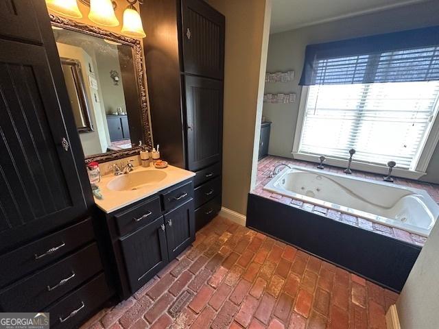 full bathroom featuring a jetted tub, vanity, and brick floor