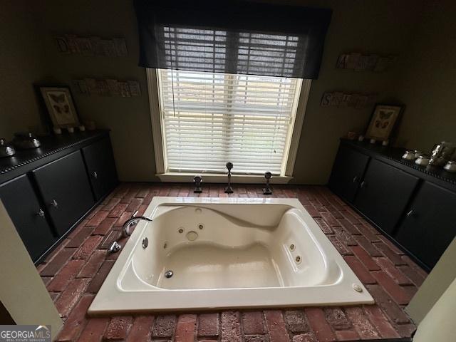 full bath featuring brick floor and a whirlpool tub