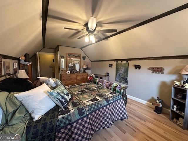 bedroom featuring ceiling fan, baseboards, light wood-style flooring, and vaulted ceiling