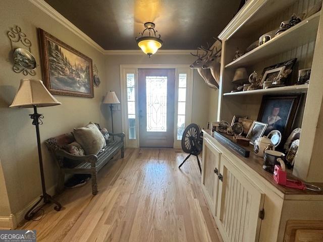 entryway with light wood-style floors and ornamental molding