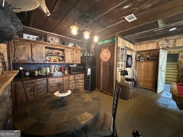 kitchen featuring visible vents, stainless steel microwave, concrete floors, decorative light fixtures, and open shelves