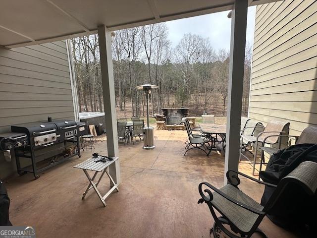 view of patio featuring outdoor dining space, a grill, and a view of trees