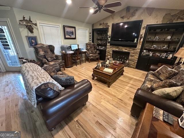 living room featuring a fireplace, a ceiling fan, lofted ceiling, and wood finished floors