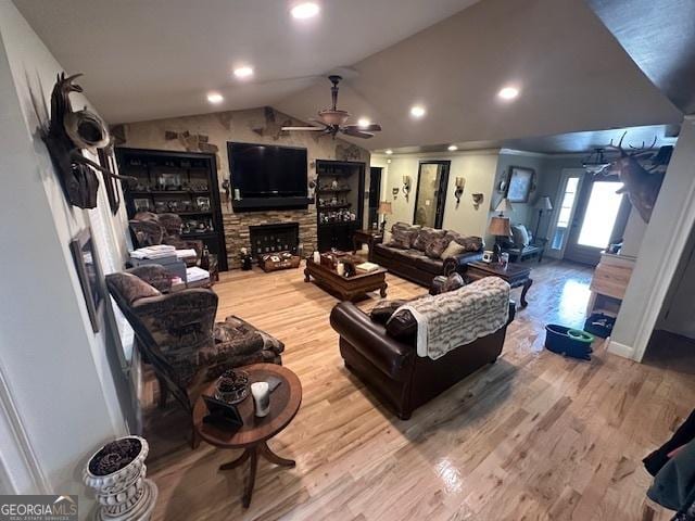 living room with ceiling fan, lofted ceiling, wood finished floors, and a fireplace