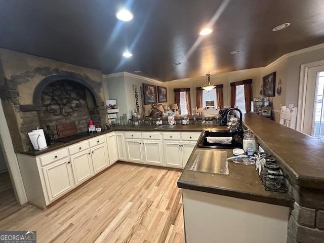 kitchen featuring dark countertops, light wood finished floors, white cabinetry, and a sink