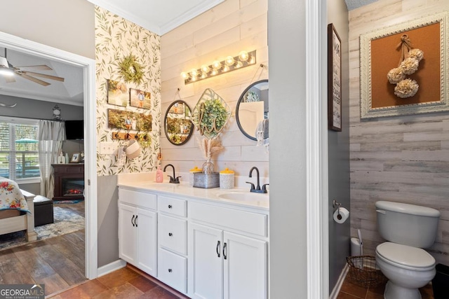 bathroom featuring crown molding, a ceiling fan, a lit fireplace, and a sink