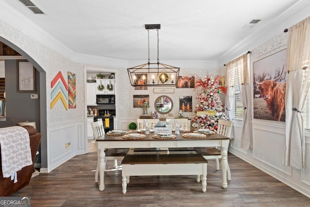 dining space with wood finished floors, visible vents, arched walkways, and ornamental molding