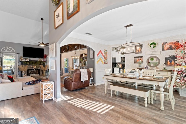 dining room with wood finished floors, visible vents, arched walkways, and ornamental molding