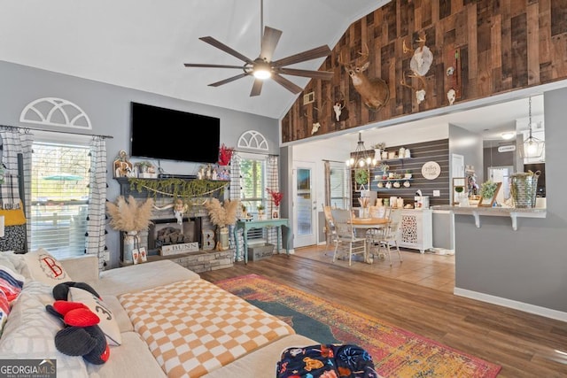 living room featuring wood finished floors, visible vents, high vaulted ceiling, a fireplace, and ceiling fan