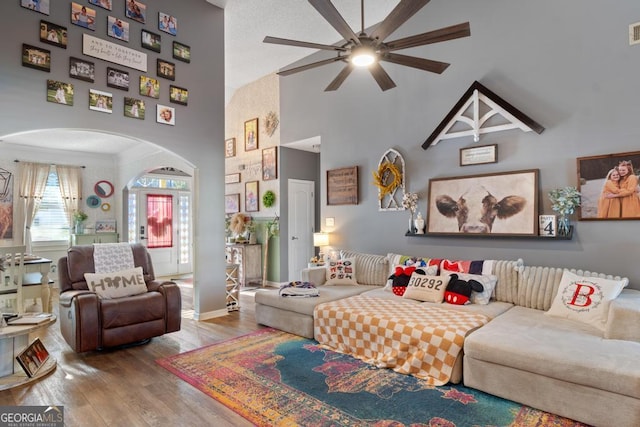 living room with visible vents, wood finished floors, arched walkways, a high ceiling, and baseboards