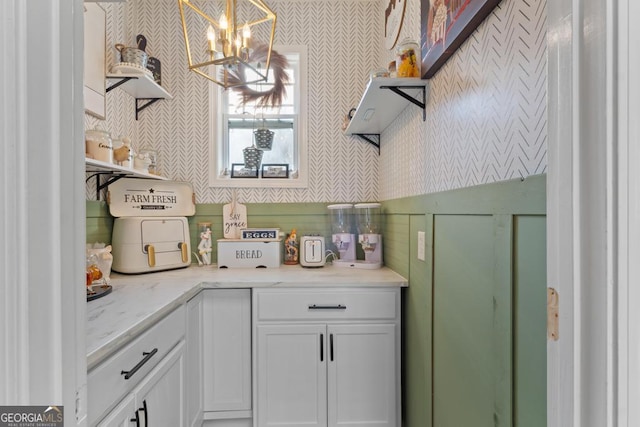 kitchen with light stone counters, white cabinetry, wallpapered walls, and open shelves