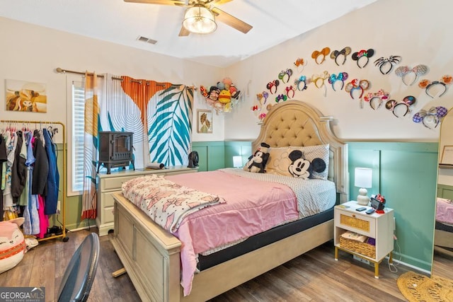 bedroom with wood finished floors, visible vents, and ceiling fan