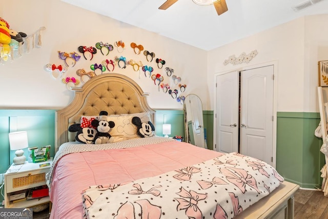 bedroom featuring a ceiling fan, wood finished floors, visible vents, and a closet