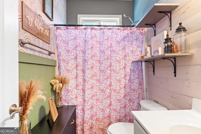 bathroom featuring curtained shower, wooden walls, toilet, and vanity