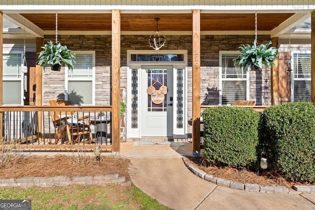 doorway to property with covered porch and stone siding