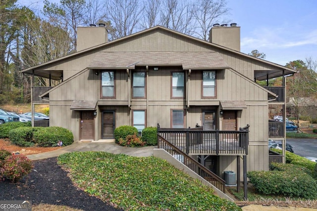 view of front of home featuring central air condition unit, a chimney, and a shingled roof