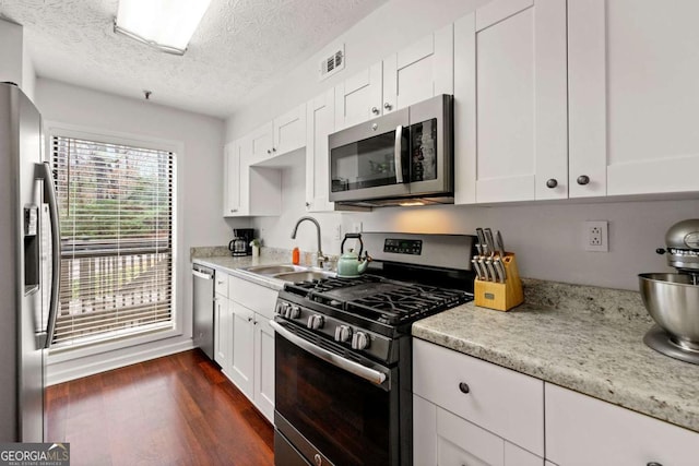 kitchen featuring a sink, appliances with stainless steel finishes, and white cabinets