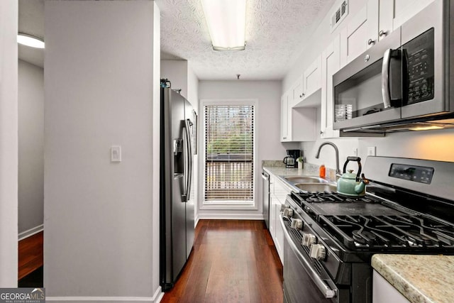 kitchen featuring visible vents, light countertops, stainless steel appliances, white cabinetry, and a sink