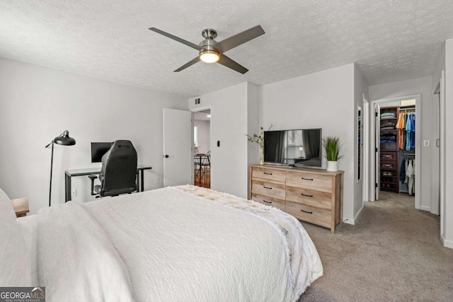 bedroom featuring baseboards, visible vents, ceiling fan, a walk in closet, and light colored carpet