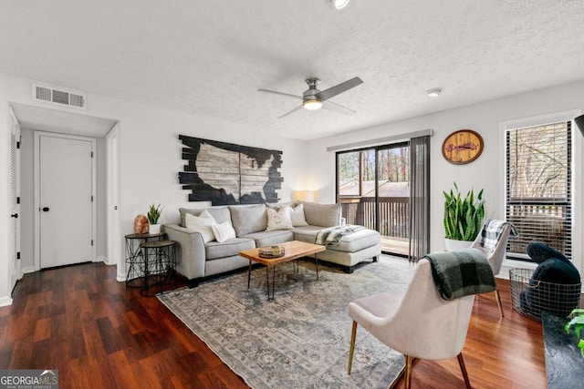 living area with a ceiling fan, wood finished floors, visible vents, and a textured ceiling