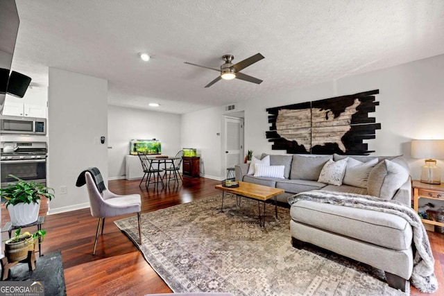 living room featuring visible vents, baseboards, a textured ceiling, and dark wood finished floors