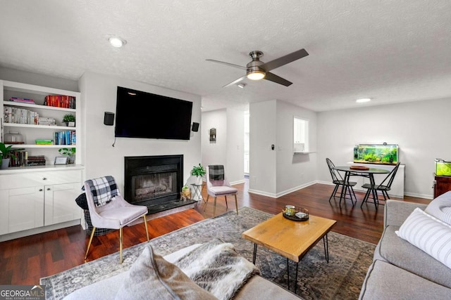 living area featuring a glass covered fireplace, a textured ceiling, and wood finished floors