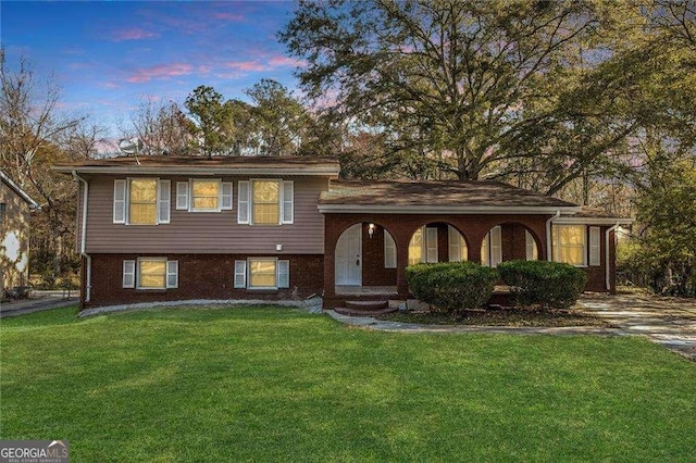 tri-level home with a lawn and brick siding