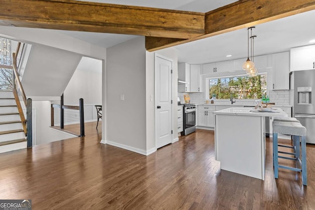 kitchen with dark wood-style floors, stainless steel appliances, decorative backsplash, light countertops, and white cabinets