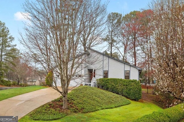 view of side of property featuring concrete driveway and a lawn