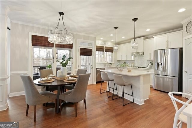 dining room with recessed lighting, ornamental molding, an inviting chandelier, and wood finished floors