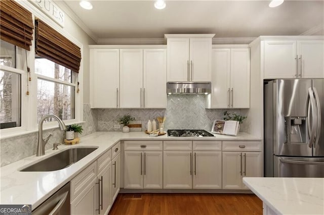 kitchen with light stone countertops, under cabinet range hood, appliances with stainless steel finishes, white cabinets, and a sink