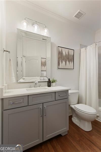 bathroom featuring visible vents, toilet, wood finished floors, crown molding, and vanity